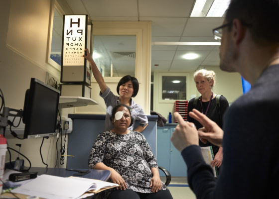 Deaf woman having her vision checked with interpreter present providing communication support