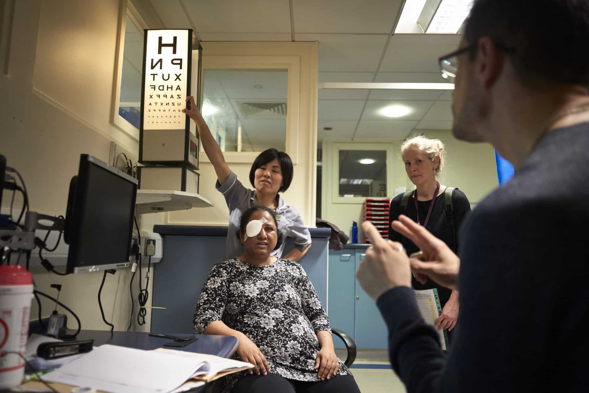 Deaf woman having her vision checked with interpreter present providing communication support